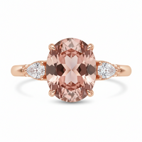 Rose gold ring with a large pink gemstone and smaller white gemstones on a white background